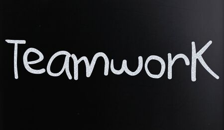 The word "Teamwork" handwritten with white chalk on a blackboardの写真素材