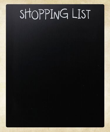 "Shopping list" handwritten with white chalk on a blackboardの写真素材