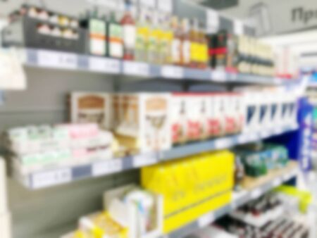 Defocused image of food and drink on shelves in illuminated store.の写真素材