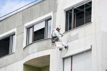Pomorie, Bulgaria - May 05, 2020: The climber performs a plaster and putty on the exterior wall of a...
