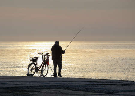 Pomorie, Bulgaria - May 11, 2020: A fisherman on the beach catches fish early in the morningのeditorial素材