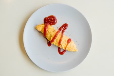 Breakfast omelette with tomato sauce on white background.の写真素材