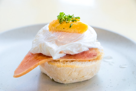 The Close up Breakfast is Egg Benedict on white plate. Eggs Benedict- toasted Thai muffins, ham, poached eggs, Spinach style.の写真素材