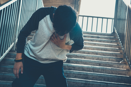 Young man having heart attack or heart failure at park. man with chest painful cramps.の写真素材