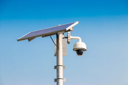 Cctv security surveillance camera system attached on the traffic light blue background.