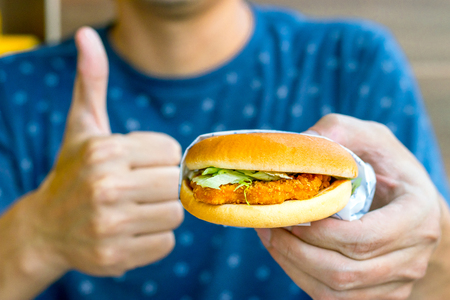 So good young man eats him delicious appetizing chicken burger. delicious burger.の写真素材