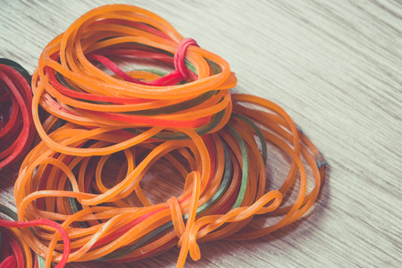 The colorful loom bands on wood background, plastic bandの写真素材