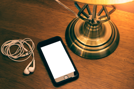 The phone open on screen blank and lamp on wood table.の写真素材