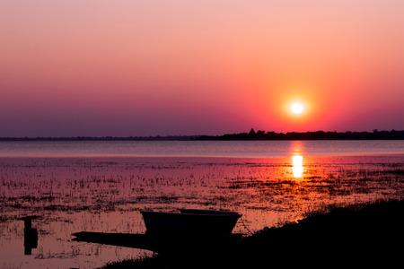 Sunset on the lake with a boat silhouette in buriram, Travel thailand.の写真素材