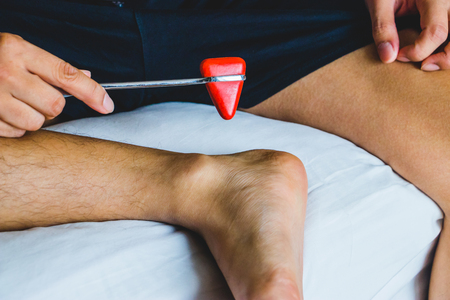 Young man testing wrist joint reflex with red hummer jerk.の写真素材