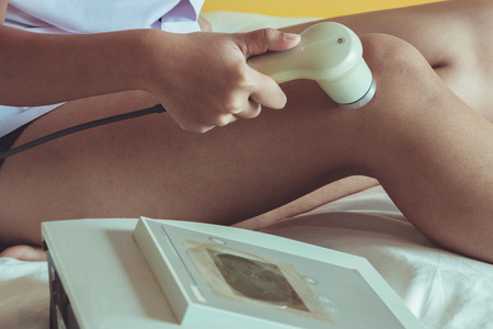 Physicaltherapist using ultrasound probe on my yourself's knee for release pain.の写真素材