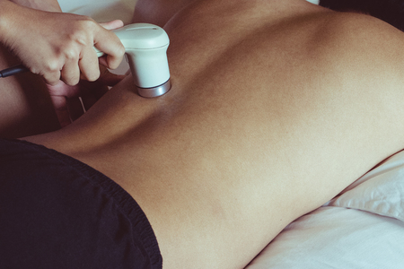 Physicaltherapist using ultrasound probe on patient back for release pain.の写真素材