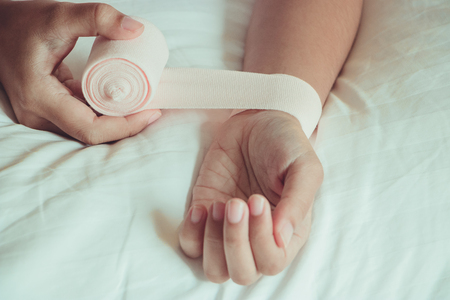 Medicine bandage on injury female wrist on yellow backgroundの写真素材