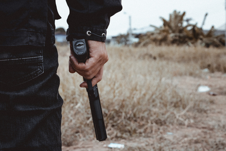 Killer holding a gun side him , cropped shot of man holding gun in hand.の写真素材