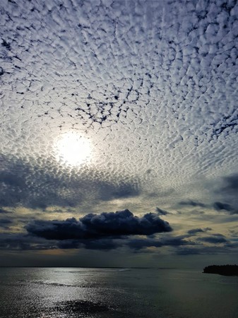 the sun shining through the clouds with ocean viewの写真素材
