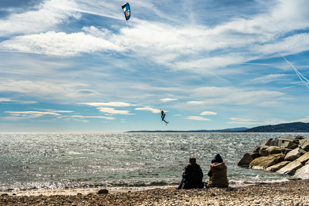 people watching a kite surfer in action on french riviera in saint raphael, franceの写真素材