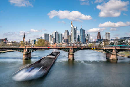 Frankfurt, Germany - March 31, 2020: frankfurt skyline view with a cargo ship passing underneath ignas bubis bridgeのeditorial素材