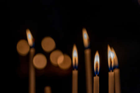 closeup of multiple burning candles with beautiful bokeh in churchの写真素材