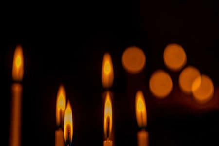 closeup of multiple burning candles with beautiful bokeh in churchの写真素材
