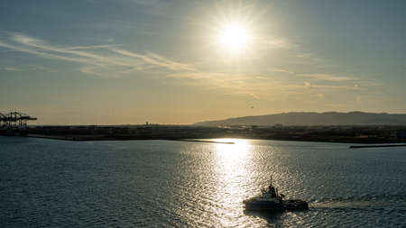 View of a golden sunset with ship in front of the sun near Barcelona waterfront, spainの写真素材
