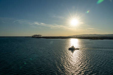 View of a golden sunset with ship in front of the sun near Barcelona waterfront, spainの写真素材