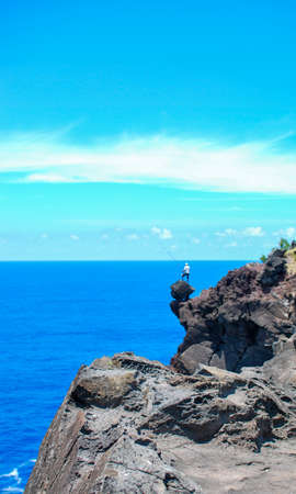 man with fishing rod standing on rocks at a deep cliff in front of the indian ocean on la reunion islandの写真素材