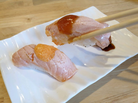 Chopsticks holding grilled japanese salmon sushiの素材