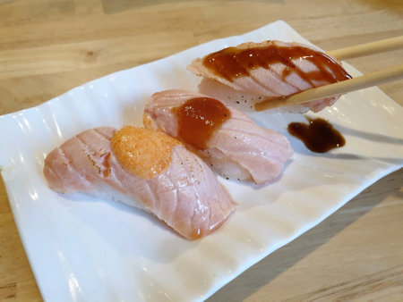 Chopsticks holding grilled japanese salmon sushiの素材