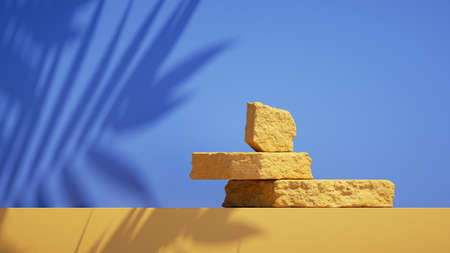 3d render, abstract simple blue yellow background with tropical leaves shadow and bright sunlight. Minimal showcase scene with cobble stones for product presentationの写真素材