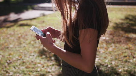 An attractive young lady using a phone in town. Medium shot 4kの写真素材