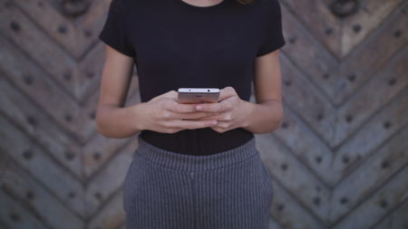 An attractive young lady using a phone in town. Medium shot 4kの写真素材