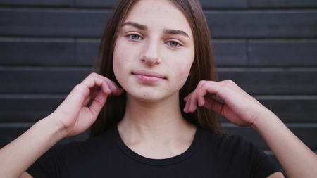 Portrait of a very beautiful modern cute girl who laughs and looks at the camera. The wind plays...