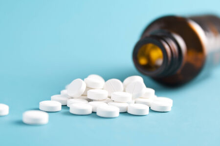 White pills and bottle on blue backgroundの写真素材