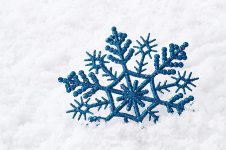 Shiny blue snowflake on snowの写真素材