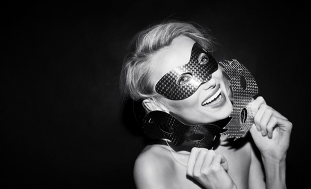 Smiling blonde beauty wearing carnival mask, looking at camera.の写真素材