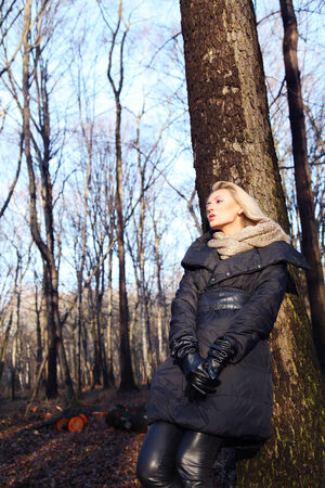 Blonde beautiful woman relaxing in forest. Girl posing in fashionable coat.の写真素材