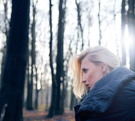 Portrait of beautiful blonde girl posing in forest. Woman looking away.の写真素材