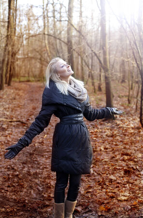 Smiling beautiful blonde woman posing in autumn forest with toothy smile.の写真素材