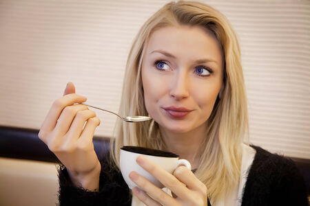 Beautiful blonde young woman relaxing, drinking coffee. Portrait.の写真素材