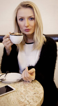 Portrait of relaxing blonde young woman drinking coffee.の写真素材