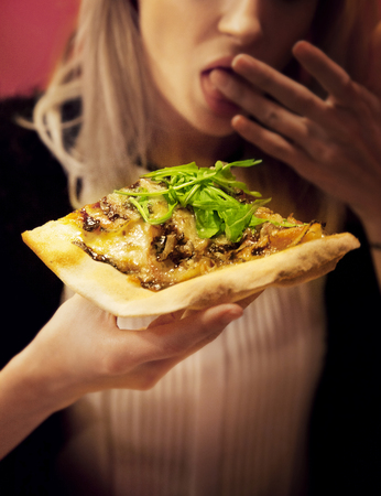 Blonde young girl eating pizza. の写真素材