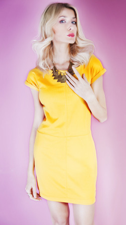 Slim young beautiful blonde woman posing in yellow fashionable dress, looking at camera. Studio shot.の写真素材