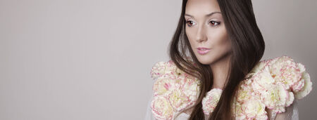 Beauty portrait of sensual brunette young woman with flowers. Girl with long healthy hait and perfect natural makeup.の写真素材