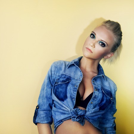 Young beautiful blonde girl posing in studio wearing fashionable jeans clothes.の写真素材