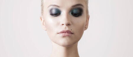 Beautiful sensual blonde woman with perfect makeup and closed eyes posing in studio. Beauty portrait.の写真素材