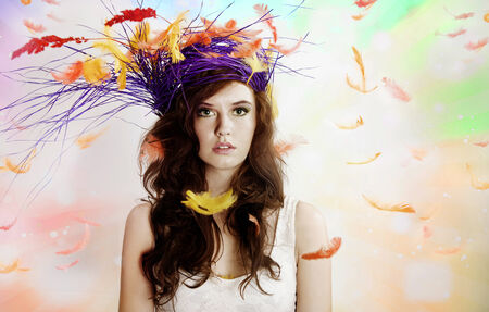 Portrait of beautiful brunette woman looking at camera, posing over flying feathers. Easter.の写真素材
