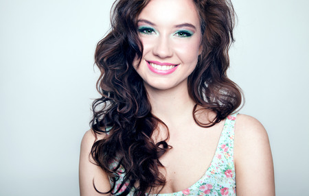 Beauty portrait of young beautiful brunette woman with toothy smile and long curly hair. Girl looking at camera.の写真素材