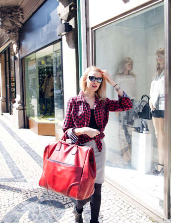 Fashionable young beautiful blonde woman walking on street, shopping の写真素材