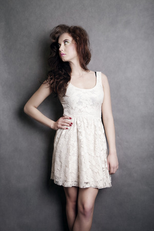 Attractive brunette woman posing wearing fashionable dress, gray .の写真素材