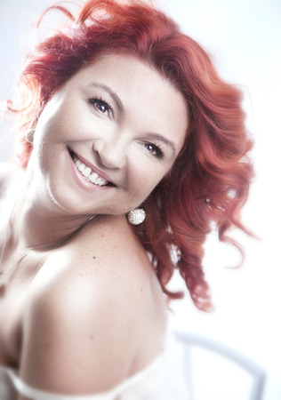 Attractive long haired beautiful woman posing with toothy smile , looking at camera. Studio shot.の写真素材